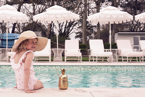 Little girl sat poolside at THE NICI with a cocktail.